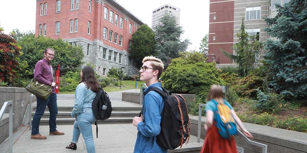   四个学生背着书包穿过四方广场